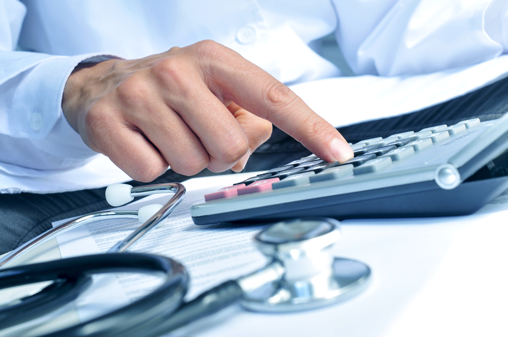 Healthcare professional calculates surgery costs on calculator, highlighting high expenses of brachial plexus repair.